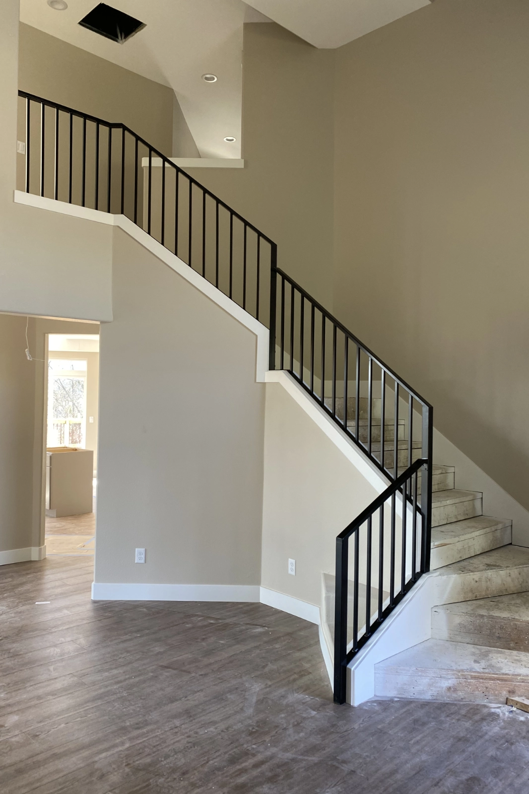 A black iron residential staircase railing featuring slim vertical pickets and a matching handrail. | Chip and Dale's Iron Works
